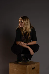 a woman crouching on a wooden box